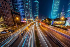 Timelapse photo of cars moving fast on the highway with tall hotels in the background